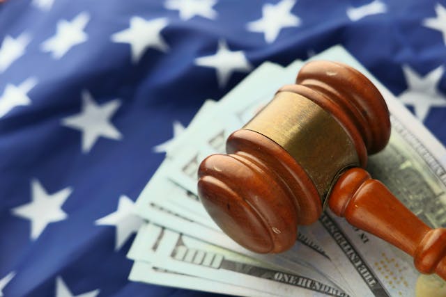 a judge's gavel and money on top of an American flag